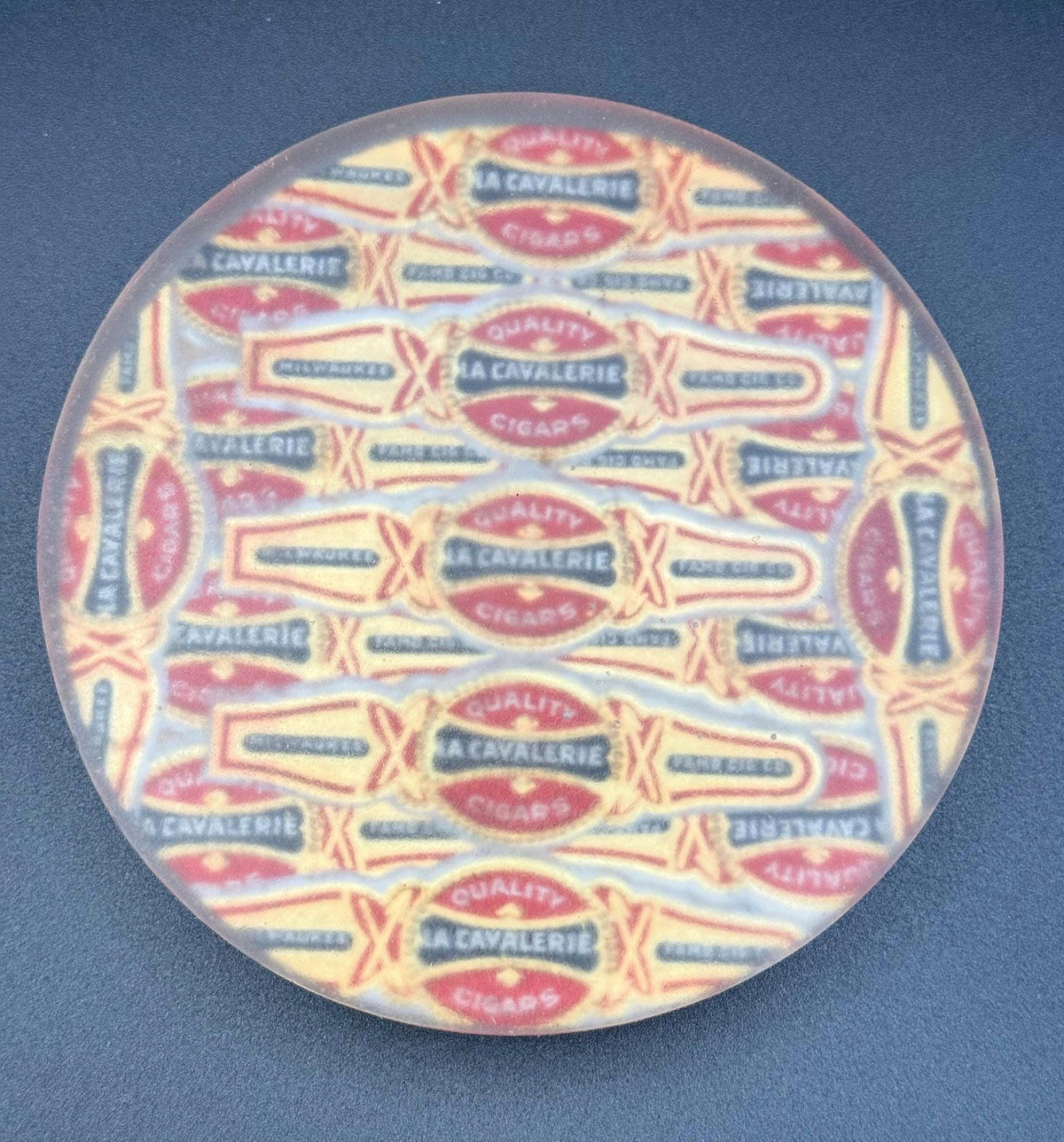 May include: A circular coaster with a repeating design of vintage cigar labels. The labels are in cream, red, and black, with the words "QUALITY" and "A CAVALERIE CIGARS". The coaster has a translucent appearance. vintage cigar, cigar coasters, cigar box art, antique cigar, whiskey coaster, bar drink coaster, cigar lounge decor, man cave decor, epoxy coasters, wood coasters, cigar gift, retro bar decor, classic bar decor